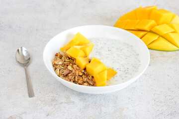 Healthy and delicious mango chia seed pudding with granola in white bowl