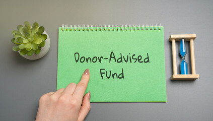 Donor-Advised Fund concept. Charitable giving vehicle that allows individuals to donate to charity and receive immediate tax benefits. Business and finance. Woman pointing at notepad with inscription