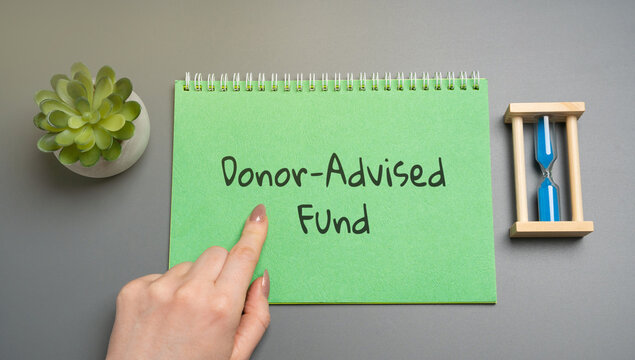 Donor-Advised Fund concept. Charitable giving vehicle that allows individuals to donate to charity and receive immediate tax benefits. Business and finance. Woman pointing at notepad with inscription