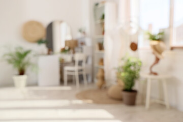 Blurred view of light makeup room with table, clothes rack and plants