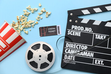 Movie clapper with cinema cinema ticket, popcorn and film reel on blue background