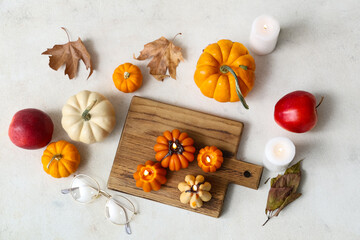 Burning candles with pumpkins, apples, eyeglasses and autumn leaves on white background