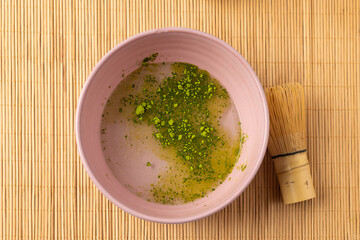 Preparing matcha green tea powder in pink bowl with bamboo whisk