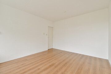 A spacious empty room featuring a light wooden floor and white walls, creating a bright and minimalist atmosphere ideal for various purposes.