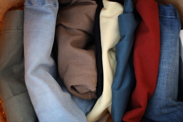 A pile of clothes with a blue shirt on top. The pile is made up of a variety of colors and textures