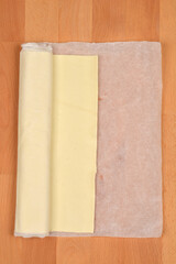 A roll of store-bought puff pastry partially unwrapped on parchment paper
