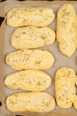 A close-up shows several golden-brown bread rolls seasoned with garlic and oregano, suggesting a...