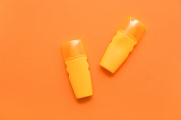 Bottles of sunscreen cream on orange background