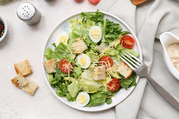 Plate with tasty Caesar salad on white background