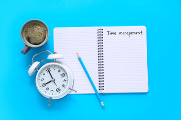 Notebook with text TIME MANAGEMENT, pencil, alarm clock and cup of coffee on color background