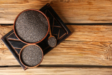 Bowls and spoon with chia seeds on wooden background