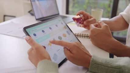 Couple using tablet and credit card to shop online through e-commerce app, making payment and browsing modern platform with promo codes and discount offers