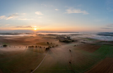 Drone shot of agricultural fields and rolling hills enlightened by sunrise