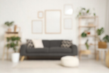 Cozy sofa, shelving unit and blank posters on white brick wall in room. Blurred view