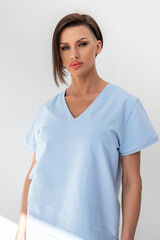 Fototapeta premium Elegant woman in light blue skirt and T-shirt on white background. Fashionable female style. Studio photography. Vertical photo