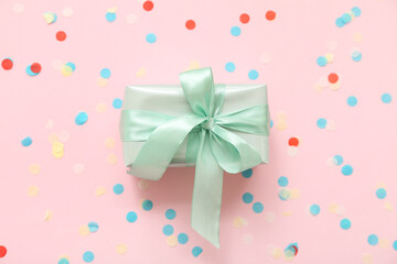 Green gift box and confetti on pink background