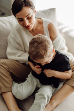 Mother embracing her son while sitting on a sofa: authentic family moments