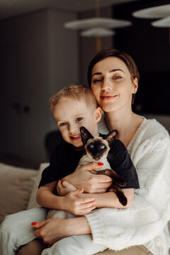 Mother and son embracing siamese kitten at home
