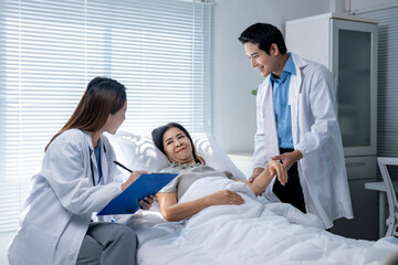 A woman is in a hospital bed with two doctors standing over her