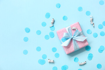 Pink gift box with silver serpentine and confetti on blue background