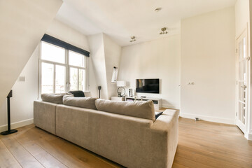 A contemporary living room showcasing minimalist furniture with a light color palette and ample natural light from windows, creating a cozy atmosphere.