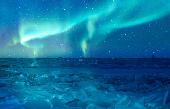 Breaking blue ice over frozen Norwegian Sea - Northern lights or Aurora borealis in the sky over Tromso, Norway