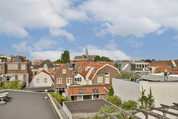 Obraz premium A scenic view of rooftops showcasing a blend of modern and historic buildings under a cloudy sky, illustrating urban beauty and architectural diversity.