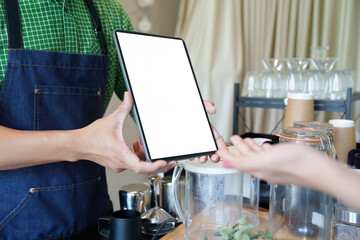 Sustainability and Customer Interaction. A barista presents a menu on a tablet, showcasing tech in promoting eco-conscious coffee options.