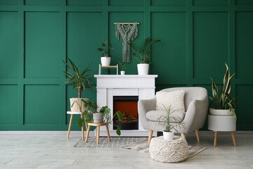 Interior of stylish living room with grey armchair, fireplace and houseplants