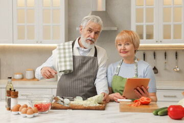 Senior couple using tablet while cooking together in kitchen