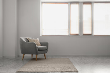 Interior of empty room with grey armchair, carpet and window