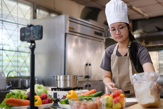 Food vlogger filming a cooking video in professional kitchen studio. - Powered by Adobe