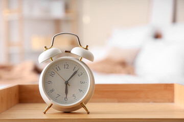 Alarm clock on wooden bedside table in bedroom, closeup