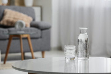 Bottle of water and glass on table in room