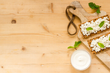 Crispy toasts with farm cottage cheese on wooden board, top view