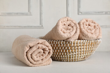 Wicker basket with rolled clean towels on light table