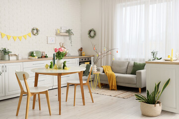 Interior of festive kitchen with sofa, tulip flowers, rabbits and baby chickens on dining table