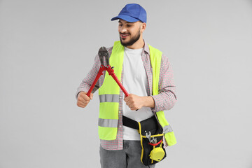 Happy male construction worker with professional plumbing wrench on grey background