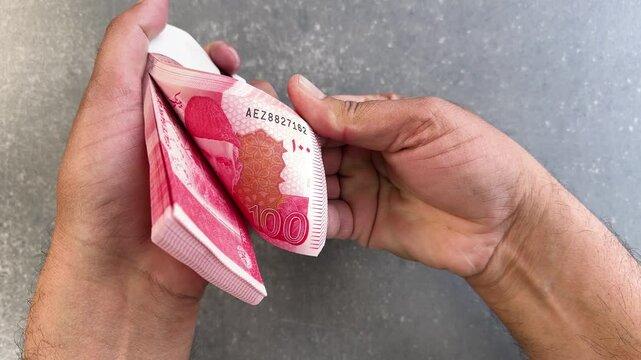 Counting Pakistan one hundred rupees notes. Close-up view