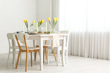 Elegant table setting with beautiful tulip flowers and candles in light dining room