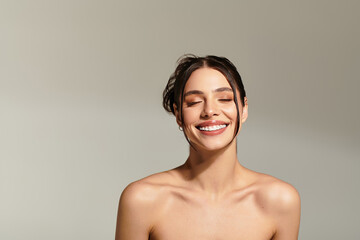 Obraz premium Joyful expression of a young beautiful woman radiating happiness in a minimalist setting