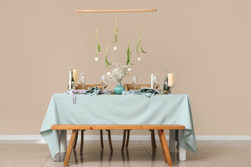 Elegant table setting with beautiful flowers, candles and hanging tulips in stylish dining room