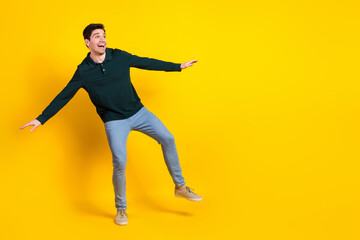 Fototapeta na wymiar Cheerful young man in casual green polo shirt posing playfully on a vibrant yellow background conveying dynamics and happiness