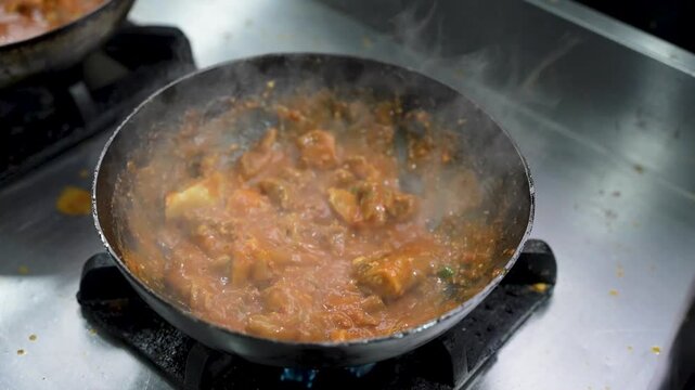 Thick, spicy Peshawari chicken karahi stirred in a wok with visible onions and masala