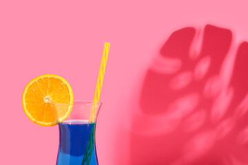 Glass of tasty cocktail and palm leaf shadow on pink background