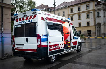White ambulance in emergency scene with a medic going inside and the lights on in the city in...