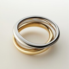A close up of three interlocking rings in gold and silver on white surface