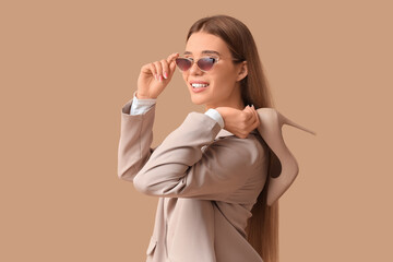 Stylish young woman with high heel on beige background