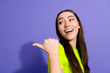 Fototapeta premium Smiling young woman gesturing confidently against a bold purple backdrop showcasing youthful energy and trendy colorful fashion.