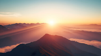 Sunrise over majestic mountain range illuminating misty valleys at dawn